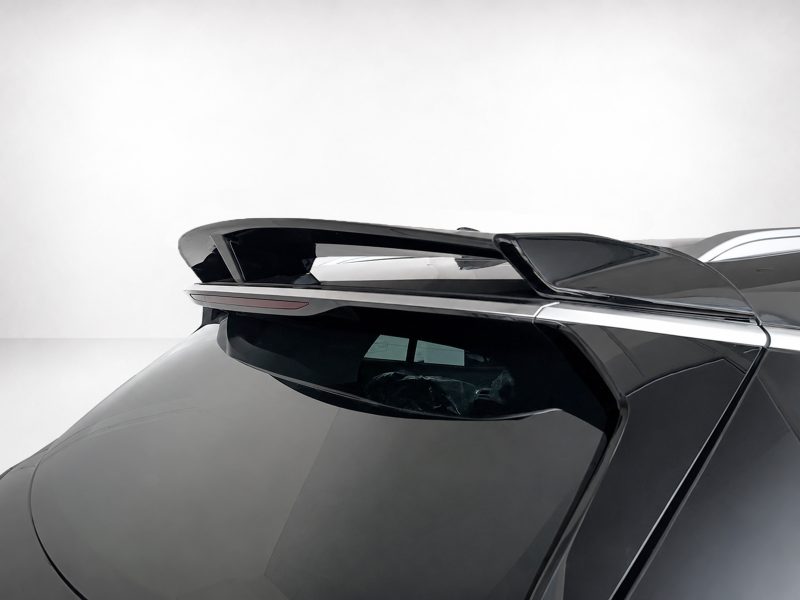 Close-up of a sleek car rear spoiler mounted above the rear window on a dark gray vehicle with glossy black panels.