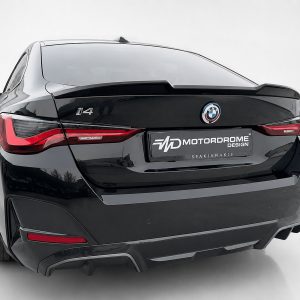 Rear view of a black BMW i4 with a Motorsport Design plate and prominent BMW badge on the trunk.
