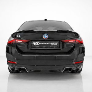Rear view of a black BMW i4 in a white studio, featuring a Motordrome Design plate.