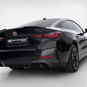 Rear three-quarter view of a black BMW sedan with a Motordrome Design plate in a studio setting