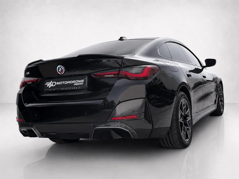 Rear three-quarter view of a black BMW sedan with a Motordrome Design plate in a studio setting