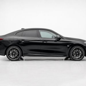 Side view of a black four-door sedan with large alloy wheels in a white studio backdrop.