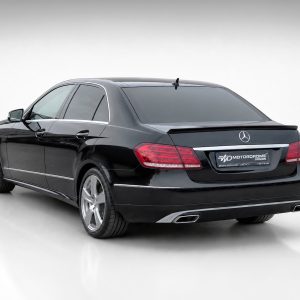 Rear three-quarter view of a black Mercedes-Benz sedan with red taillights in a studio setting