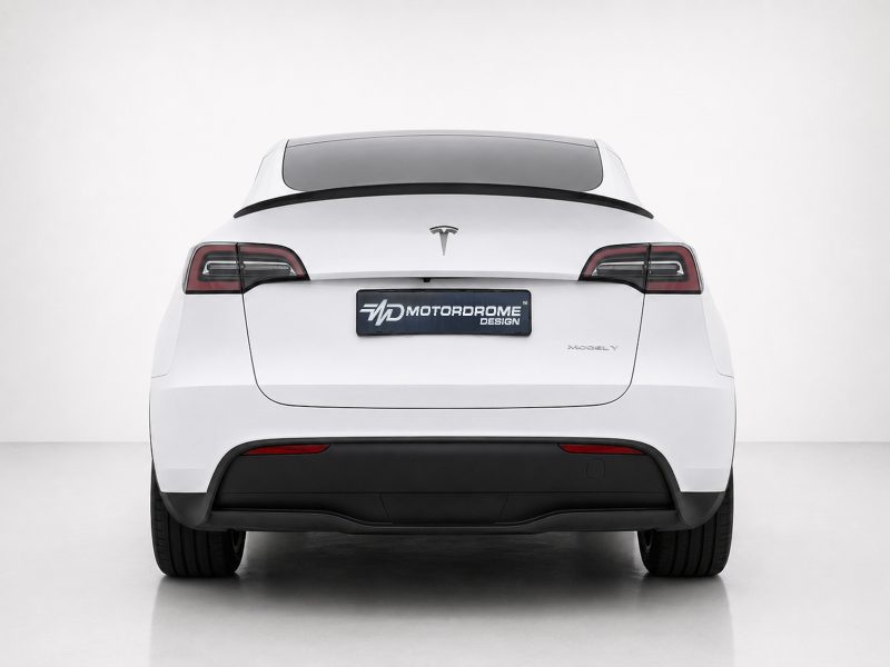 Rear view of a white Tesla Model Y with a dark rear window and red-taillights, displaying a Motordrome Design plate badge on the trunk.