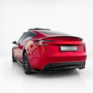 Rear three-quarter view of a red Tesla sedan in a white studio, featuring a rear spoiler and dark alloy wheels.