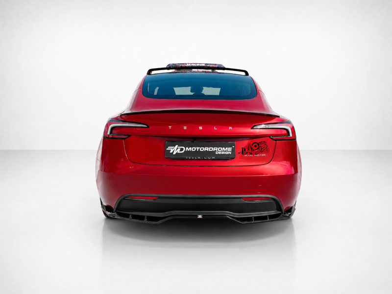 Rear view of a red Tesla in a studio, featuring aftermarket decals on the trunk and a custom plate, spoiler, and dual taillights.