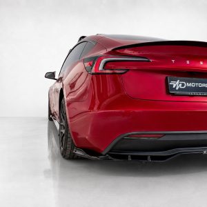 Red Tesla rear quarter view in a clean studio setting, showing taillights and a Motordrome Design plate on the back.