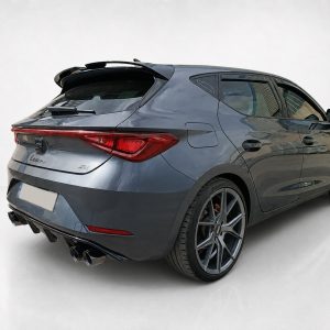 Rear three-quarter view of a dark gray sporty hatchback with large multi-spoke wheels and quad exhausts.