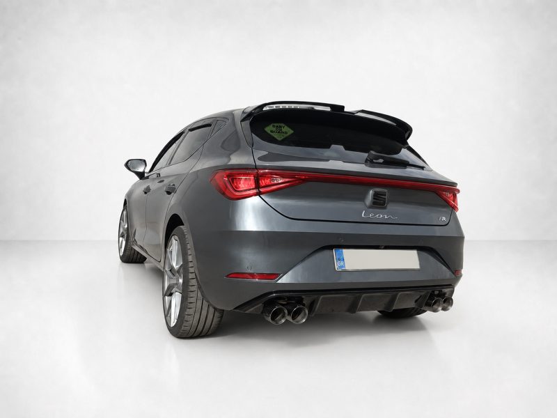 Rear three-quarter view of a gray SEAT Leon FR hatchback in a studio with a white backdrop, showing dual exhausts and red taillights.
