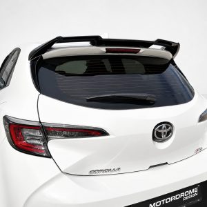 White Toyota hatchback rear view with a large black spoiler, visible rear windshield wiper, and red taillights against a light background