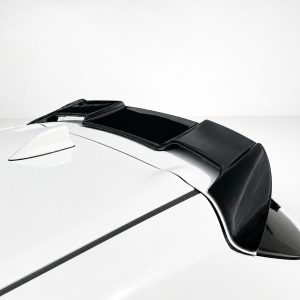 A-511_3jpg - OPSHOLDERS Close-up of a black rear spoiler mounted on a white car, extending along the roofline toward the back.