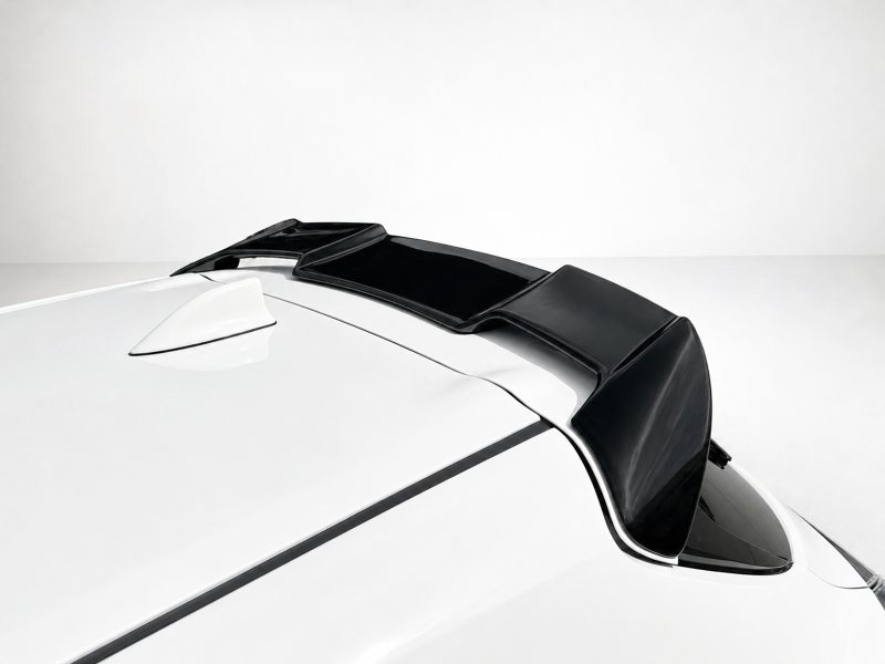 A-511_3jpg - OPSHOLDERS Close-up of a black rear spoiler mounted on a white car, extending along the roofline toward the back.