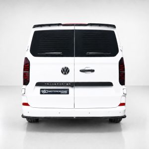 Rear view of a white Volkswagen Transporter van with split doors, dark rear windows, and a Motorodome Design badge on the bumper area.