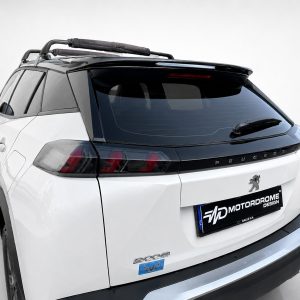 Rear-right view of a white Peugeot SUV with a black-tinted rear window and a roof rack, photographed in a studio.
