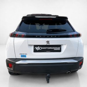 A-513_4jpg - OPSHOLDERS Rear view of a white Peugeot SUV with a Motordrome Design plate, Peugeot emblem, and tow hitch visible under the bumper.