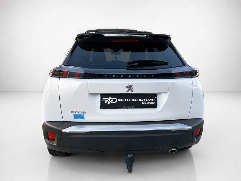 A-513_4jpg - OPSHOLDERS Rear view of a white Peugeot SUV with a Motordrome Design plate, Peugeot emblem, and tow hitch visible under the bumper.