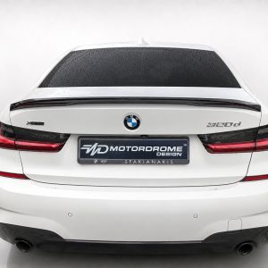 Rear view of a white BMW 520d with a dark rear windscreen and red taillights, displaying a MOTOR DROME DESIGN plate on the trunk.