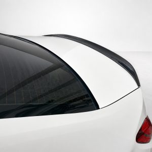 Close-up of a white car's rear end, showing the curved rear window with defroster lines and a black roof spoiler.