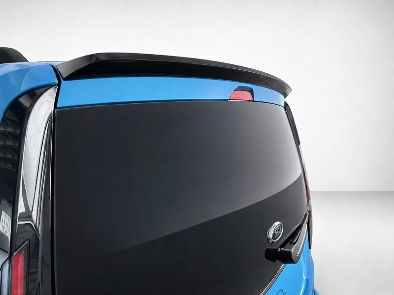 A-516_5jpg - OPSHOLDERS Rear view of a blue vehicle's back, showing a large dark rear window and a small black spoiler on the hatch.