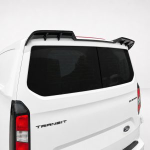 A-517_4jpg - OPSHOLDERS Rear of a white Ford Transit cargo van with black roof rack and tinted back window against a light backdrop.