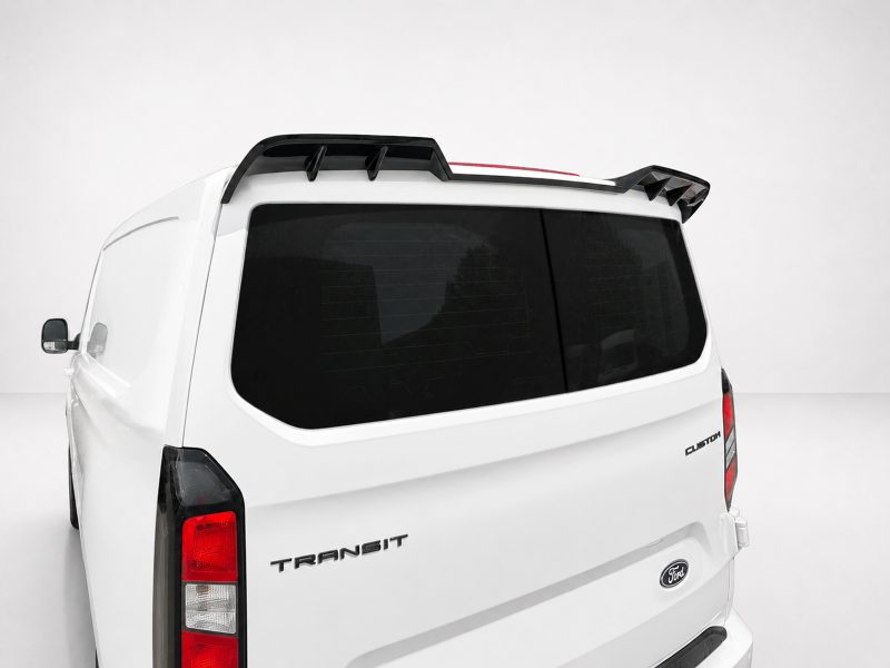 A-517_4jpg - OPSHOLDERS Rear of a white Ford Transit cargo van with black roof rack and tinted back window against a light backdrop.
