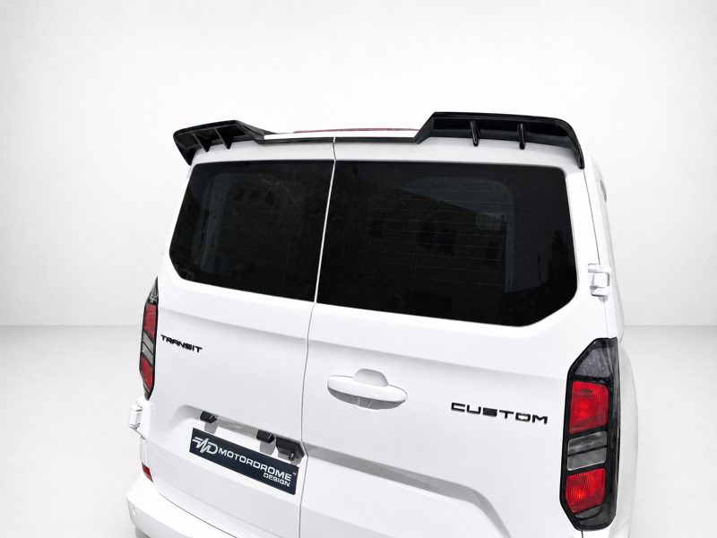 White van rear view with dark glass windows and a black roof spoiler; badge reads Transit Custom on the tailgate.
