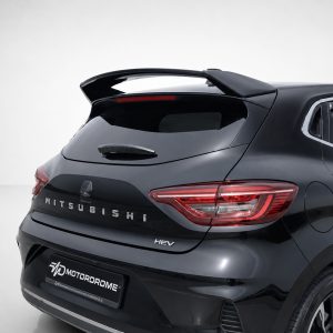 Rear view of a black Mitsubishi SUV/hatchback with a prominent sporty spoiler, red taillights, and HEV badge in a studio setting.