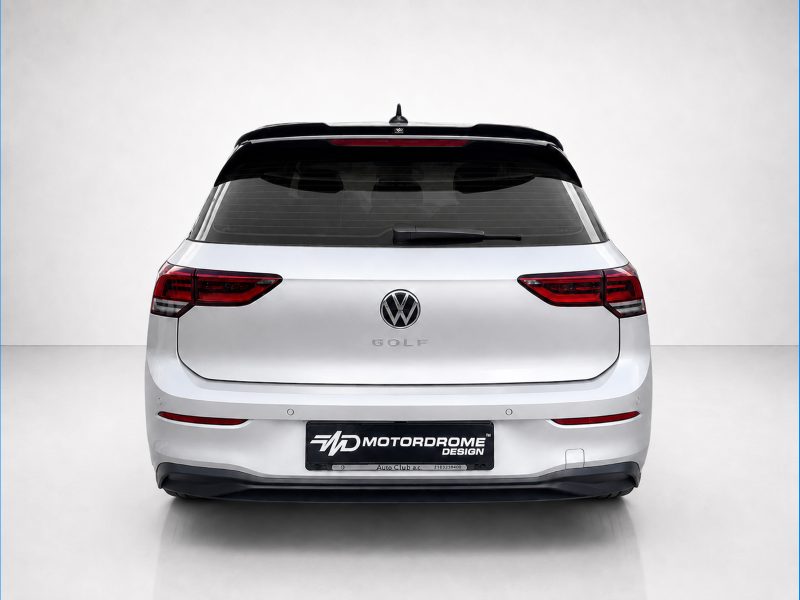 A-522_3jpg - OPSHOLDERS Rear view of a silver Volkswagen Golf hatchback in a studio setting, showing taillights and VW emblem on the trunk lid with a Motorodrome Design plate below.