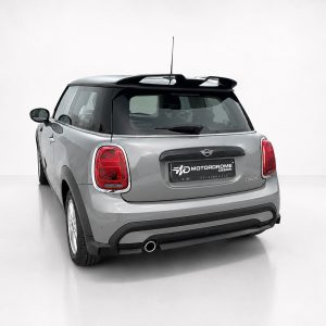 Rear view of a silver Mini Cooper in a studio, highlighting the taillights and branded license plate area.