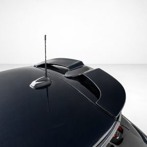 Close-up of a glossy black car roof featuring a slim antenna and a subtle rear spoiler against a light background.
