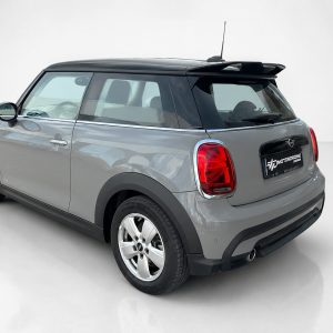 Grey Mini Cooper rear three-quarter view with black roof and red taillights in a studio setting