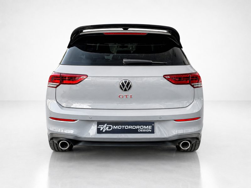 A-525_3jpg - OPSHOLDERS Rear view of a silver Volkswagen GTI hatchback with a Motordrome Design plate and dual exhausts, visible in a studio setting.