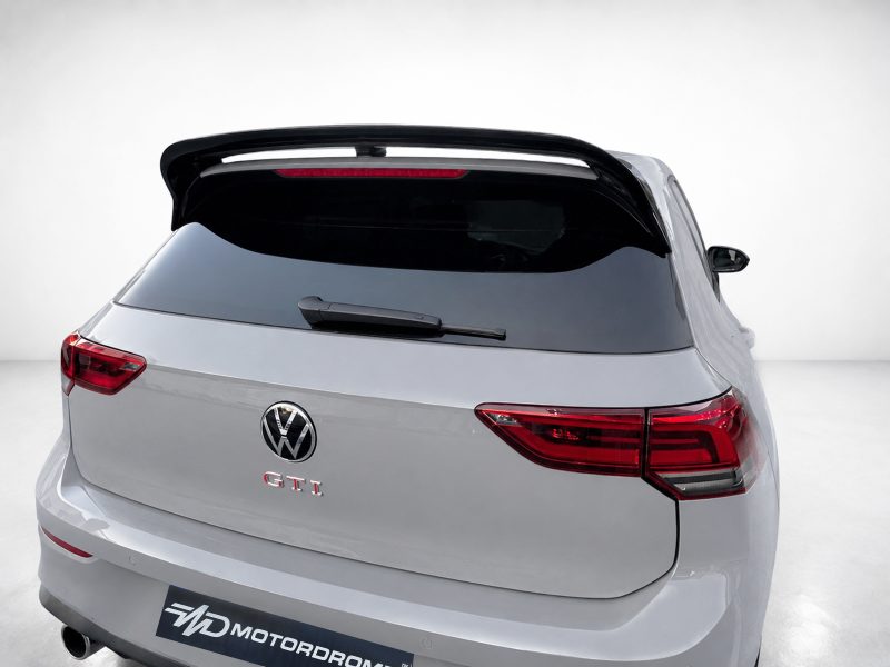 A-525_5jpg - OPSHOLDERS Rear view of a silver Volkswagen GTI hatchback in a studio, featuring a large black spoiler and red taillights.