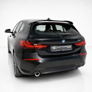 Rear view of a black BMW 118i hatchback in a white studio with red taillights and branded plate area