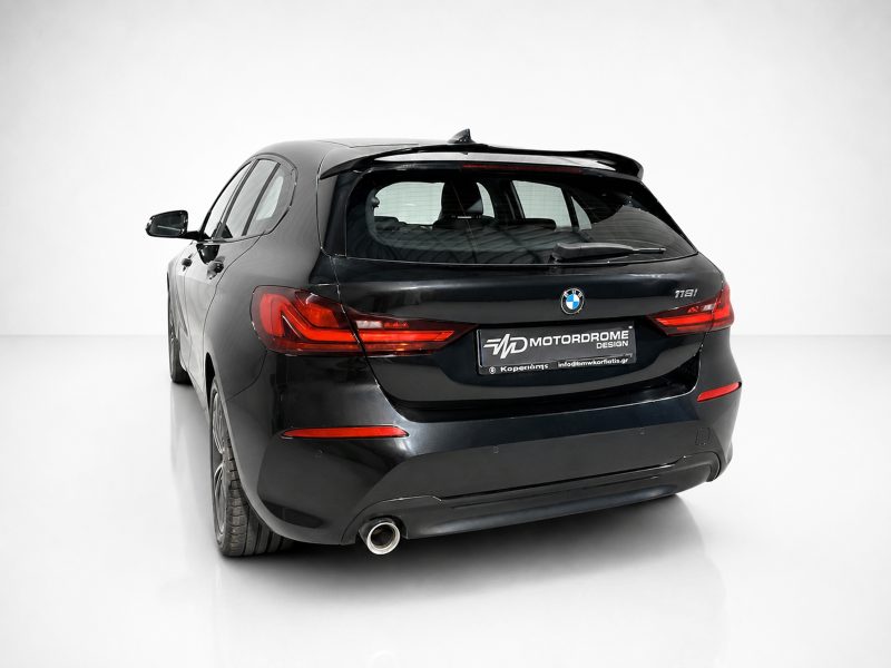 Rear view of a black BMW 118i hatchback in a white studio with red taillights and branded plate area