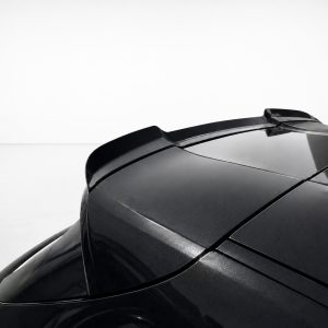 Close-up of a glossy black sports car rear roof with an integrated spoiler against a white studio backdrop.
