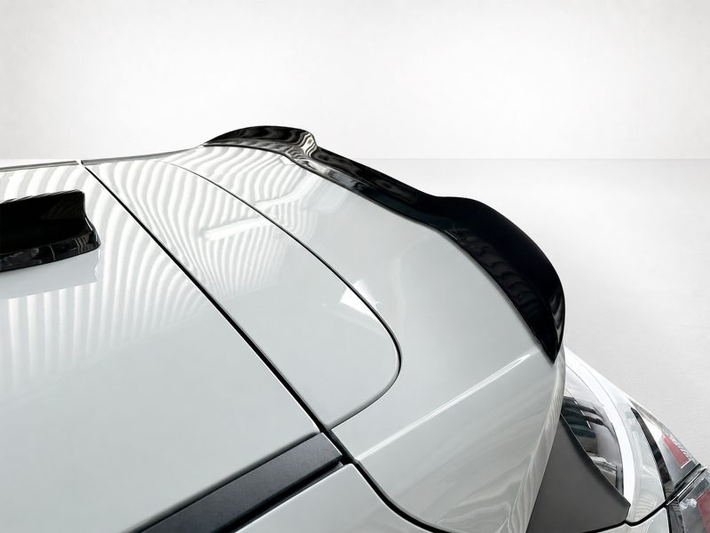 A-531_4jpg - OPSHOLDERS Close-up of a white sports car’s rear roof with black spoiler and glossy panels, highlighting sleek aerodynamic lines.