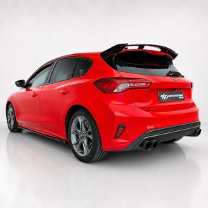 Red hatchback car seen from the rear-left, highlighting a large spoiler and dual exhausts in a studio setting on a gray background.