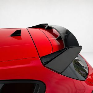 Close-up of a red car's roof showing a rear spoiler, shark-fin antenna, and rear window.