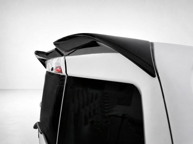 Rear view of a white SUV featuring a glossy black spoiler mounted on the rear hatch, with a dark rear window and red taillight visible on the left.