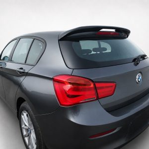 Rear three-quarter view of a dark gray BMW hatchback in a studio setting with red taillights visible behind the rear window spoiler.