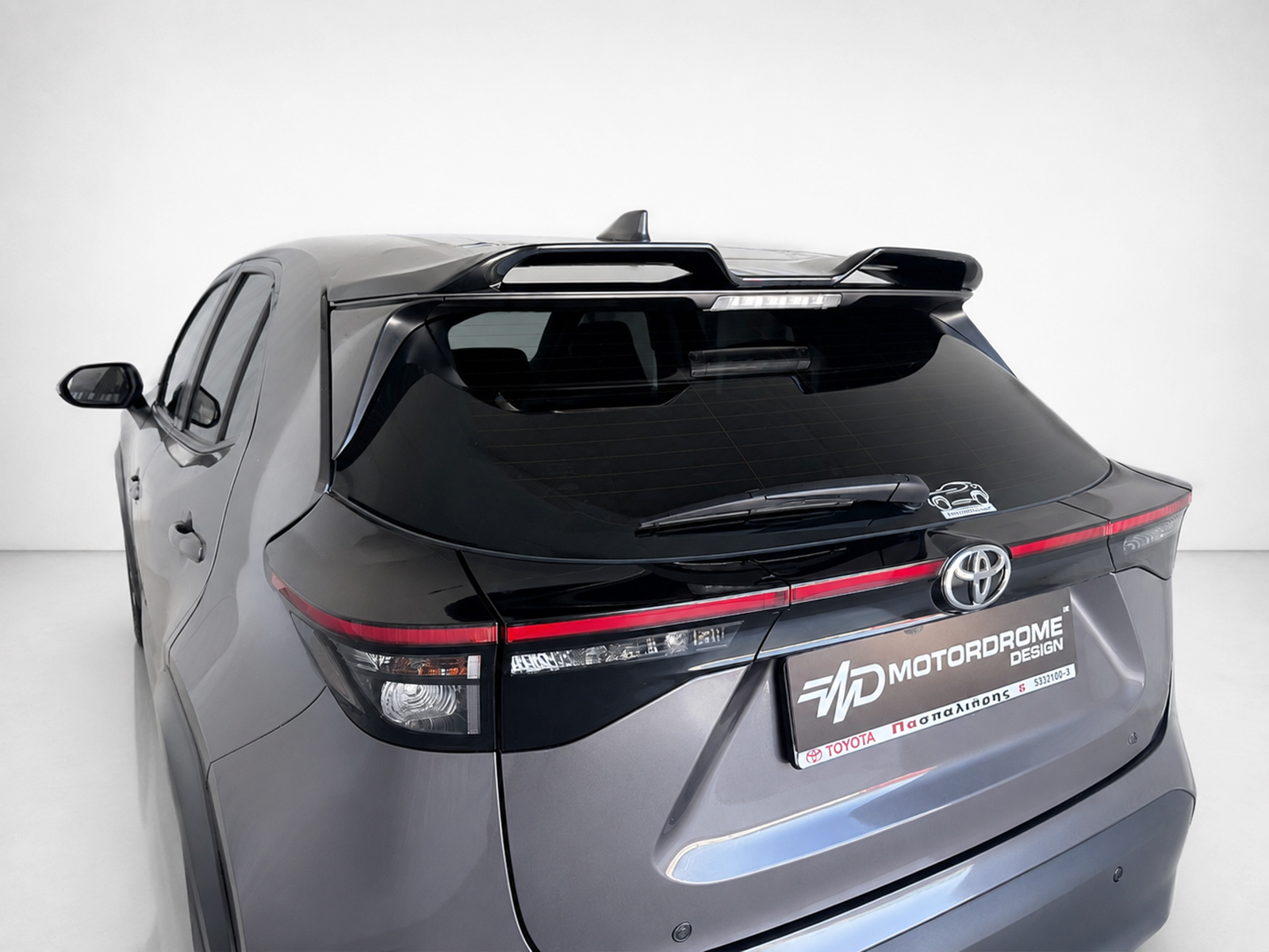 A-536_1jpg - OPSHOLDERS Rear view of a gray SUV with a roof spoiler, taillights, and a branded license plate area reading MOTORDROME DESIGN.