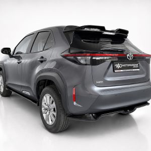 A-536_2jpg - OPSHOLDERS Rear three-quarter view of a gray Toyota Yaris SUV in a white studio backdrop, showing taillights and rear spoiler with a branded license plate area