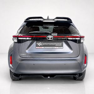 A-536_3jpg - OPSHOLDERS Rear view of a metallic gray Toyota Yaris in a studio, showing the tail lights and a MD Motordrome Design plate on the hatch.
