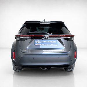 A-537_2jpg - OPSHOLDERS Rear view of a blue Toyota Yaris hatchback in a showroom, with a Motordrome Design license plate displayed on the tailgate.