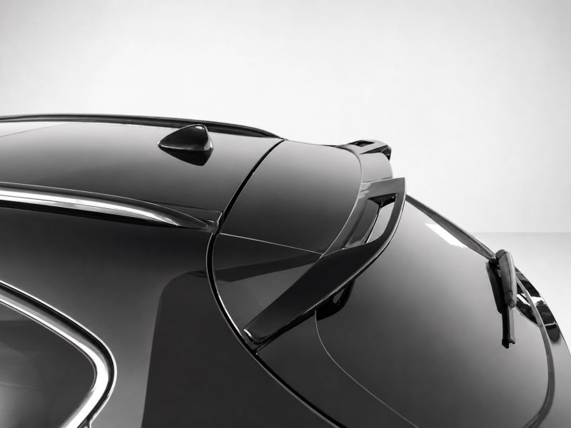 Close-up of a glossy vintage car hood with chrome trim and a rear spoiler detectible in silhouette.