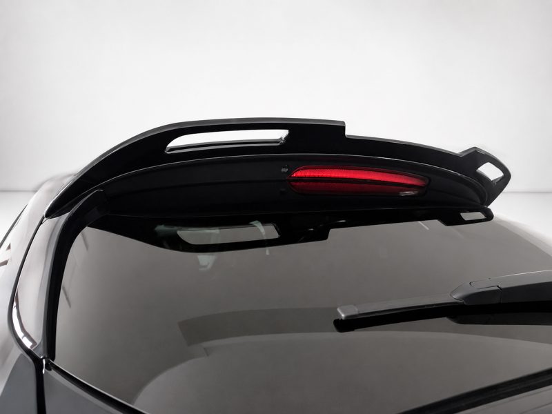 Rear spoiler with integrated red brake light on top of a dark car hatchback
