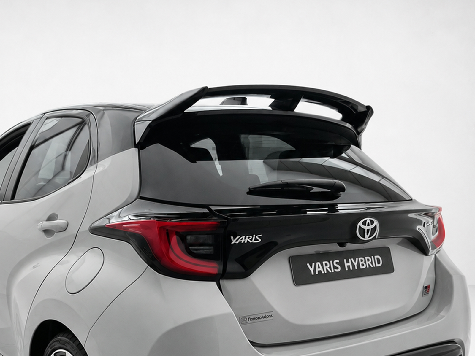 A-541_1jpg - OPSHOLDERS Rear view of a silver Toyota Yaris Hybrid, showing taillights, logo, and 'YARIS HYBRID' badge on the hatchback