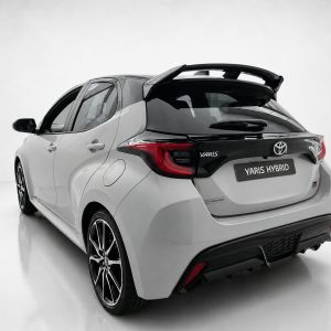 A-541_2jpg - OPSHOLDERS Rear three-quarter view of a white Toyota Yaris Hybrid hatchback in a studio setting with a black roof spoiler
