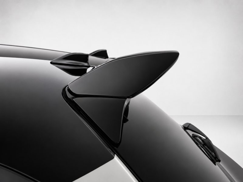 A-541_5jpg - OPSHOLDERS Close-up of a glossy black car spoiler on a sleek vehicle, highlighting its aerodynamic shape and reflections.